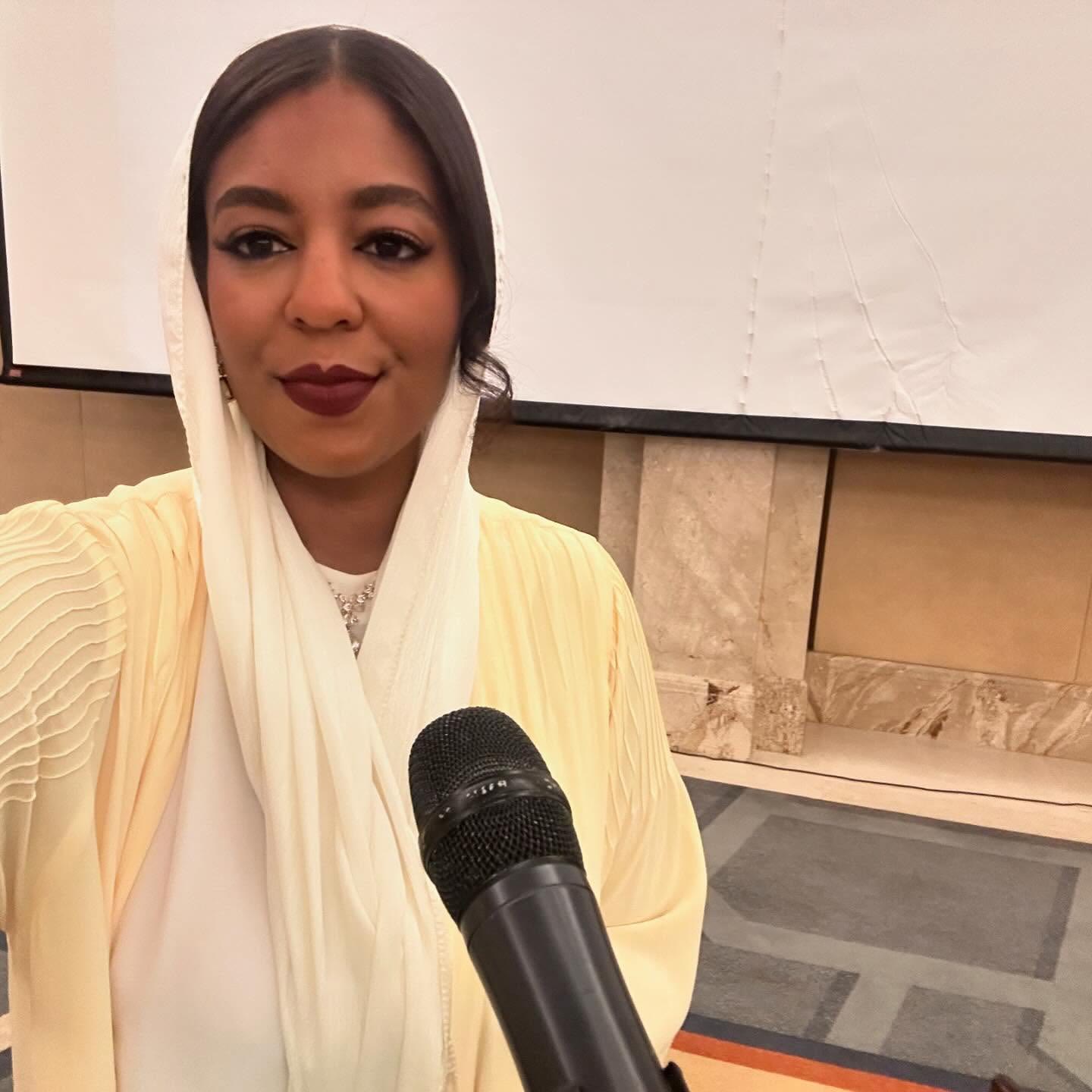 Asma in white with a microphone